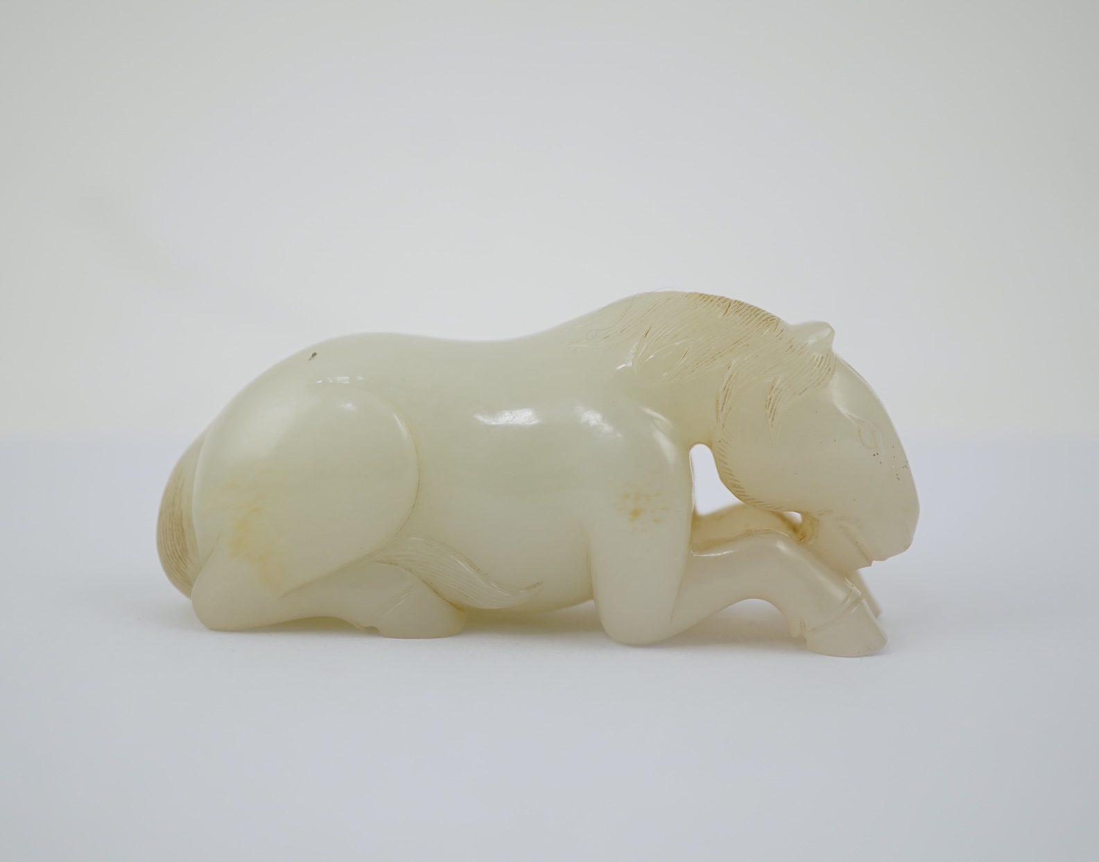 A Chinese white jade figure of a recumbent horse